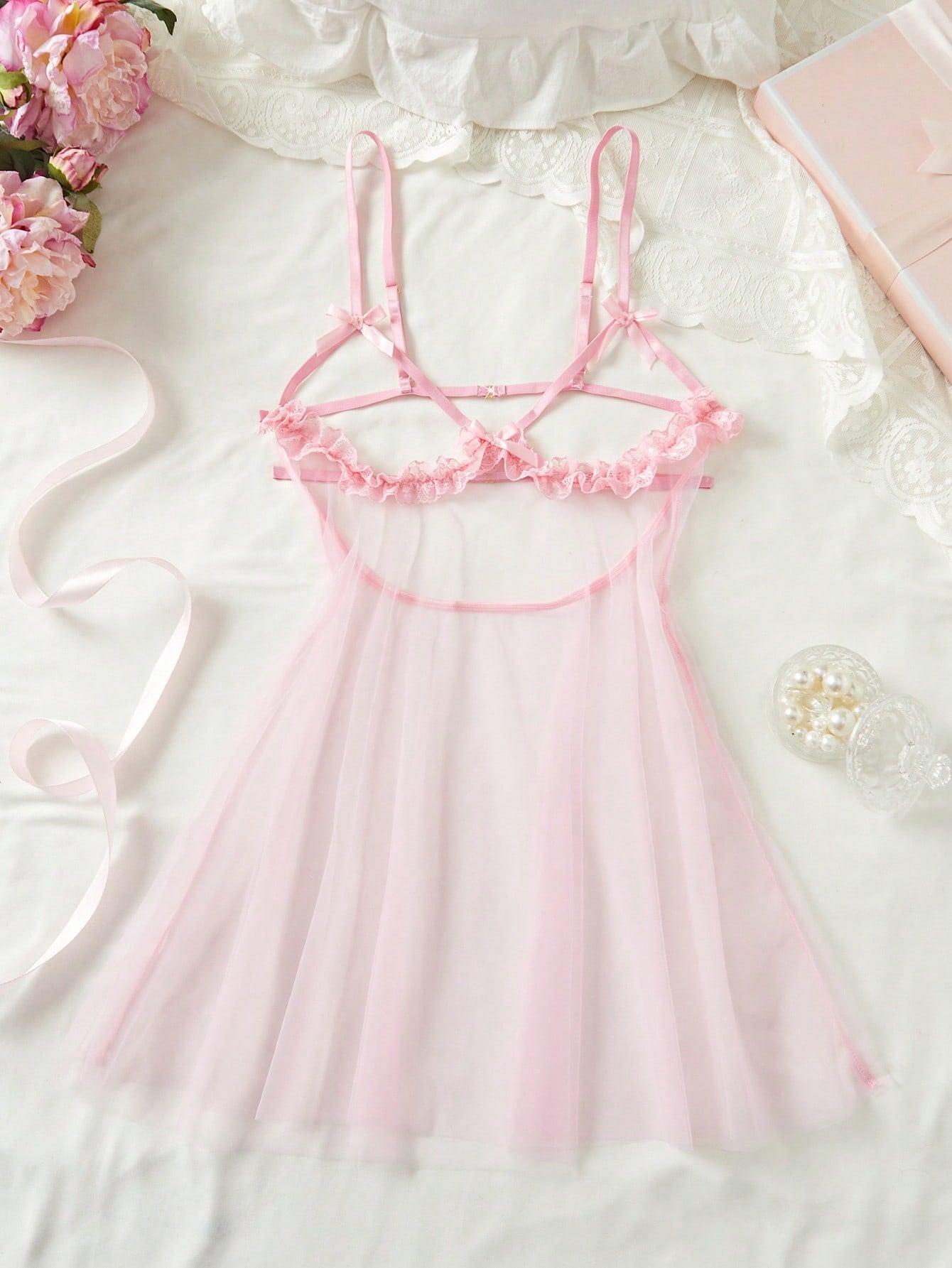 Women's baby pink babydoll nightgown with sheer backless design, bow detail, plunge neckline, adjustable straps, and short slip silhouette.