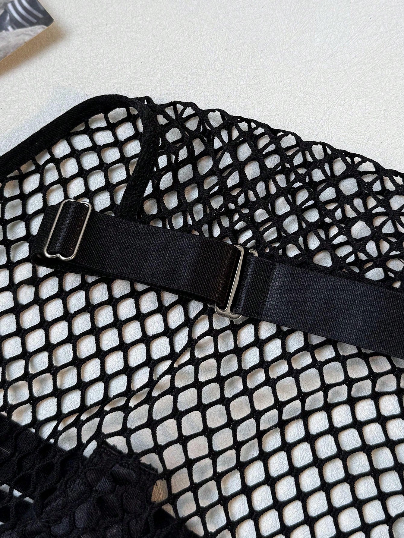 Black women's fishnet lingerie set with hollow out detail, halter underwire top, and low-rise thong in sheer mesh fabric.