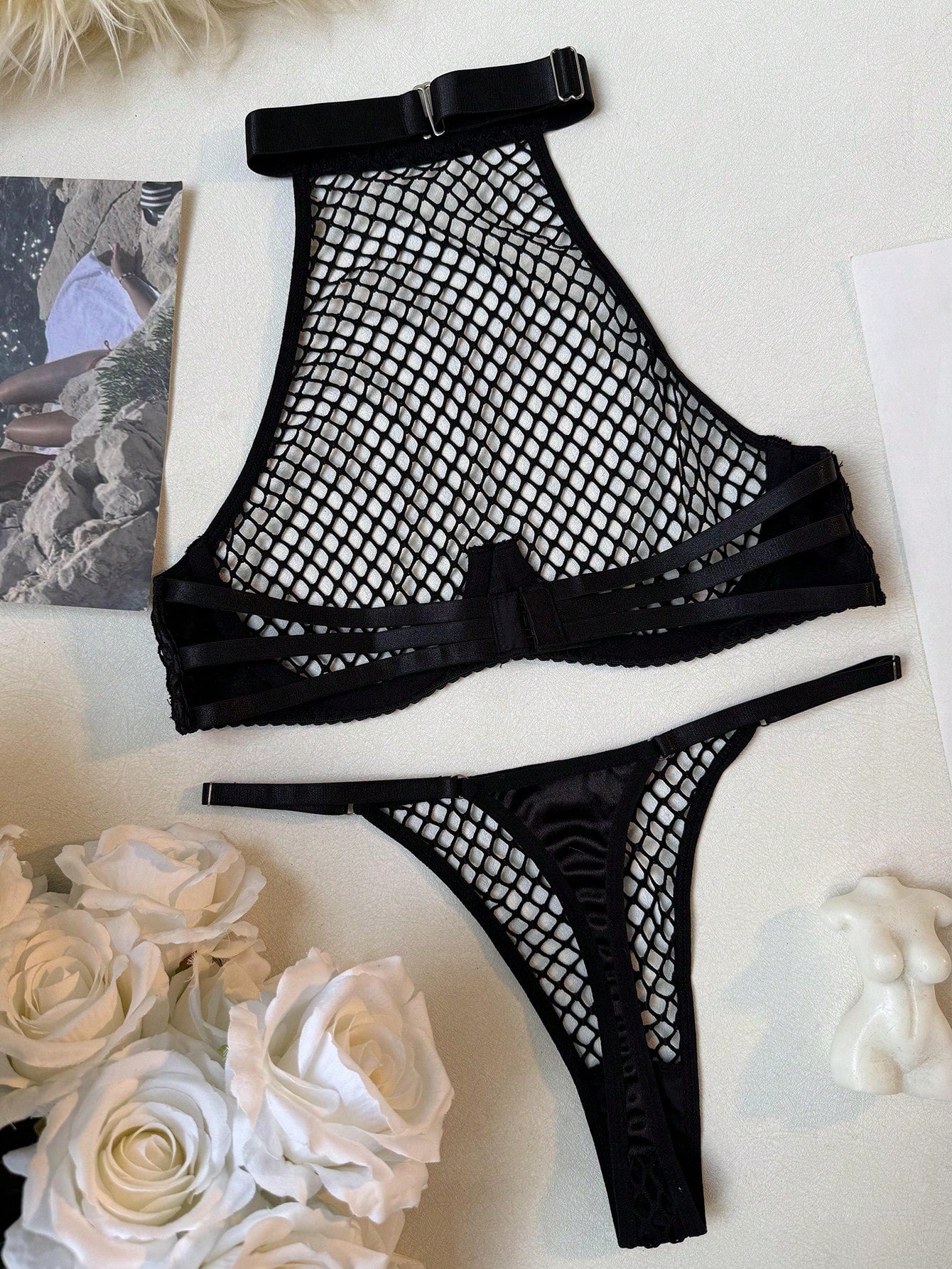 Black women's fishnet lingerie set with hollow out detail, halter underwire top, and low-rise thong in sheer mesh fabric.