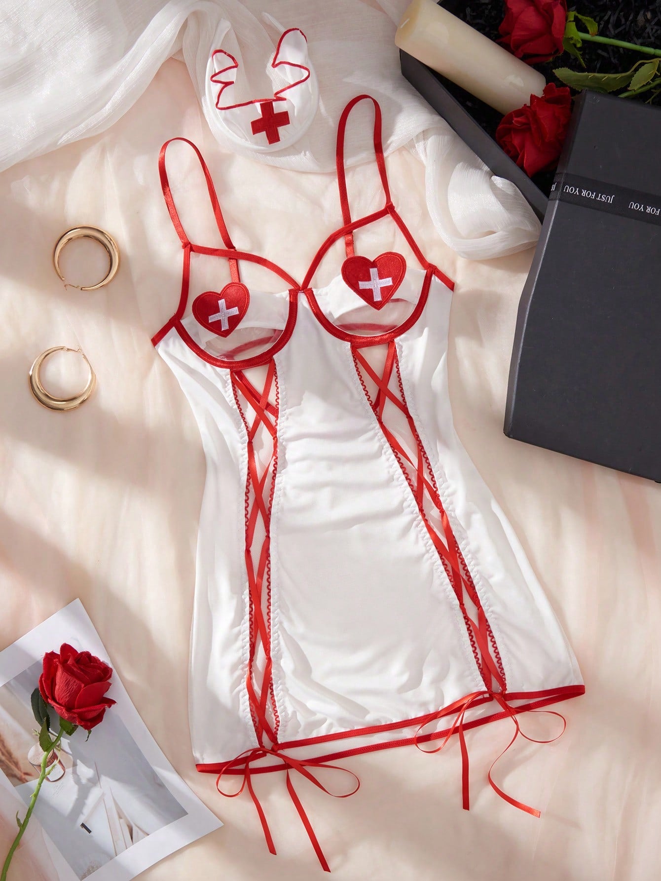 Women's 2-piece nurse babydoll lingerie set with sheer backless slip dress, side slit, adjustable spaghetti straps, matching V-string, and nurse cap in red and white.