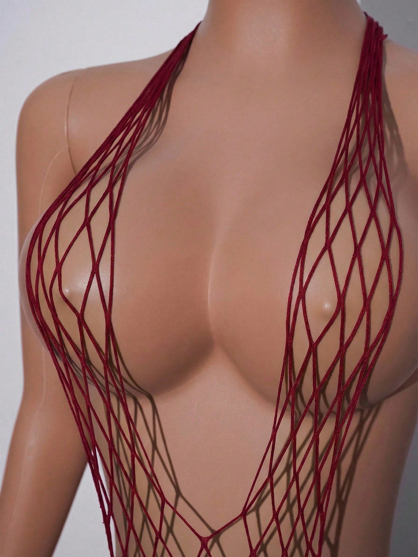 Women's burgundy sheer fishnet bodysuit with halter neckline, lace-up hollow out details, adjustable straps, and sleeveless Y2K styling.