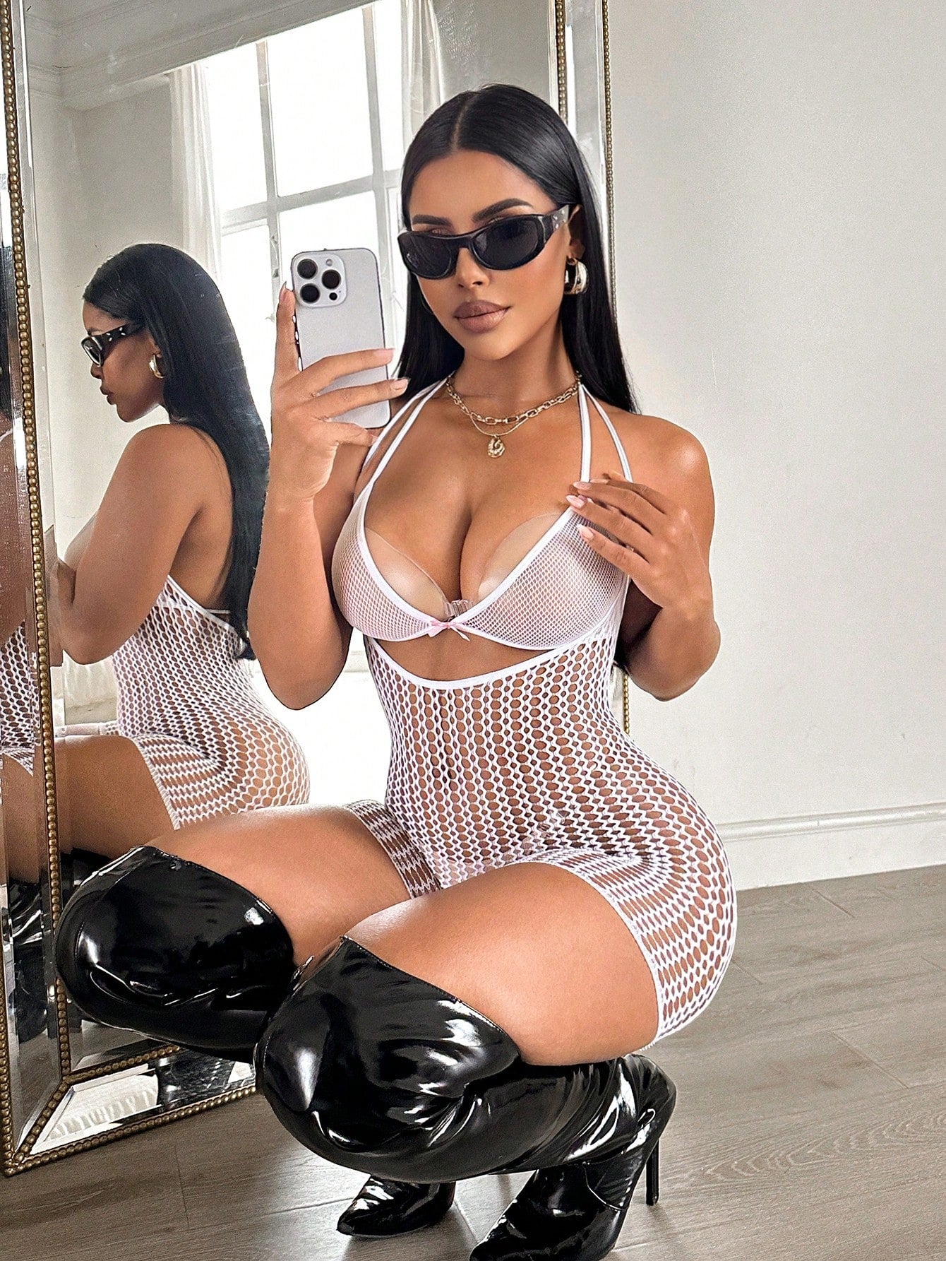 Women's sheer fishnet lingerie set with halter-style top, short bodysuit silhouette, adjustable straps, hollow out details, bow accent, and V-string bottom.