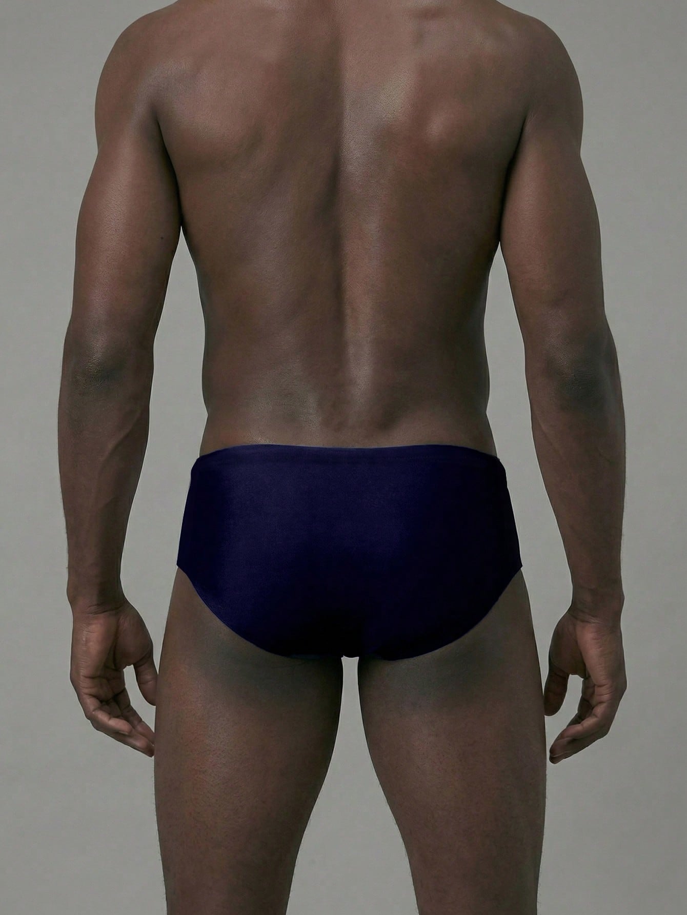 Navy blue men's swim briefs with colorblock design, cut-out detail, high waist, and short length in medium-stretch polyamide elastane fabric.
